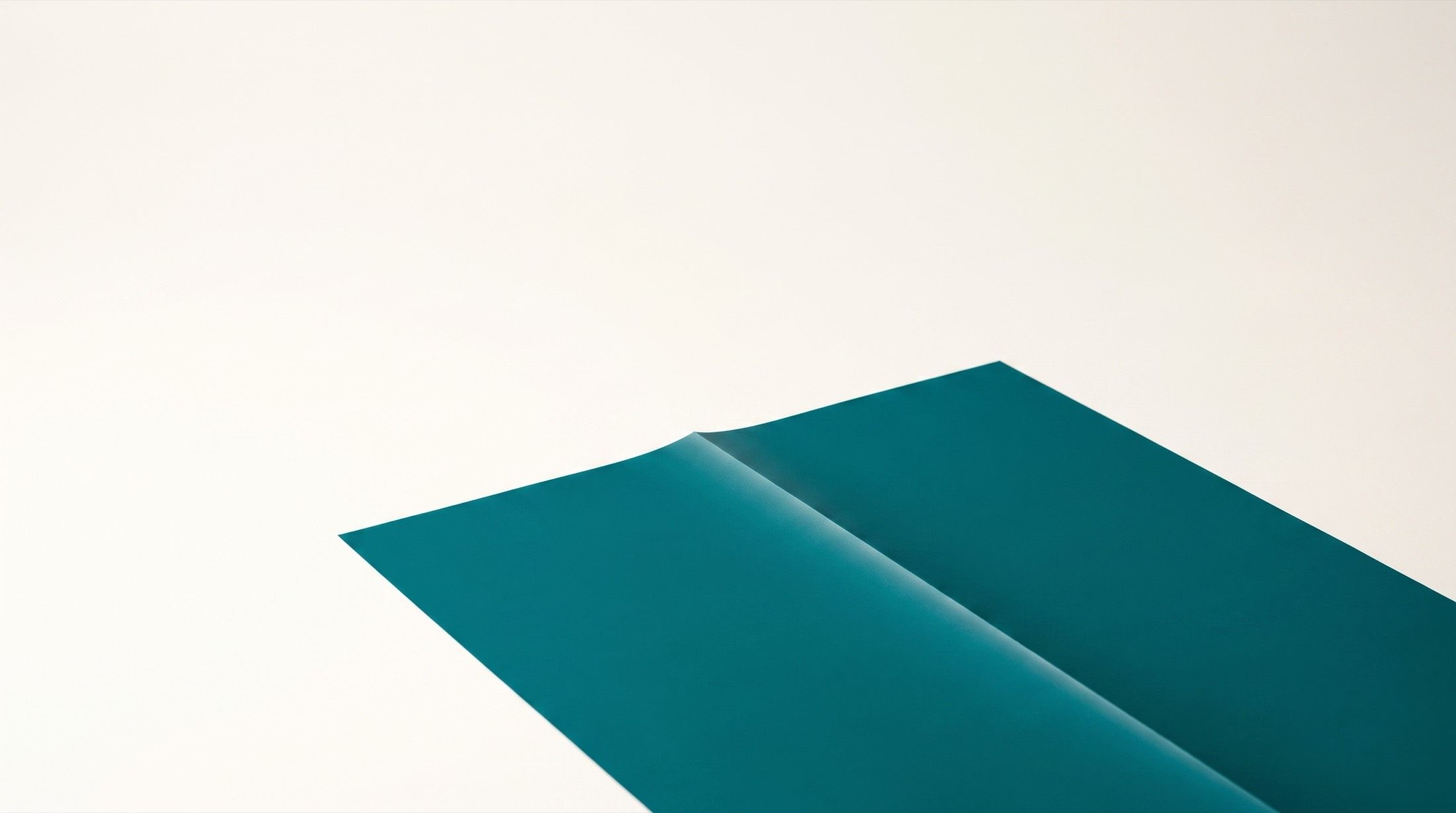 Pliego de papel verde azulado doblado sobre fondo crema.